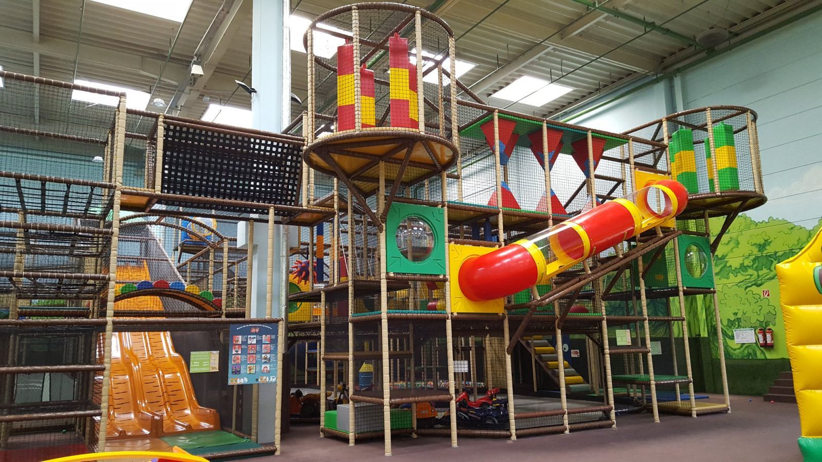 Bunte, mehrstöckige Kletter- und Rutschenlandschaft im TobiDu-Indoorspielplatz mit Tunneln, Netzen und Röhrenrutsche