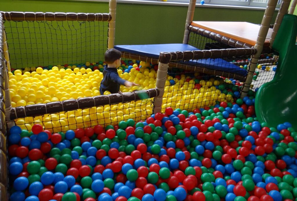 Kind spielt im bunten Bällebad mit gelben, roten, blauen und grünen Bällen im TobiDu Indoorspielplatz
