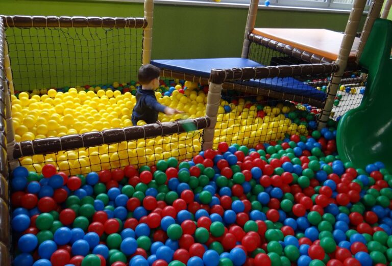 Kind spielt im bunten Bällebad mit gelben, roten, blauen und grünen Bällen im TobiDu Indoorspielplatz